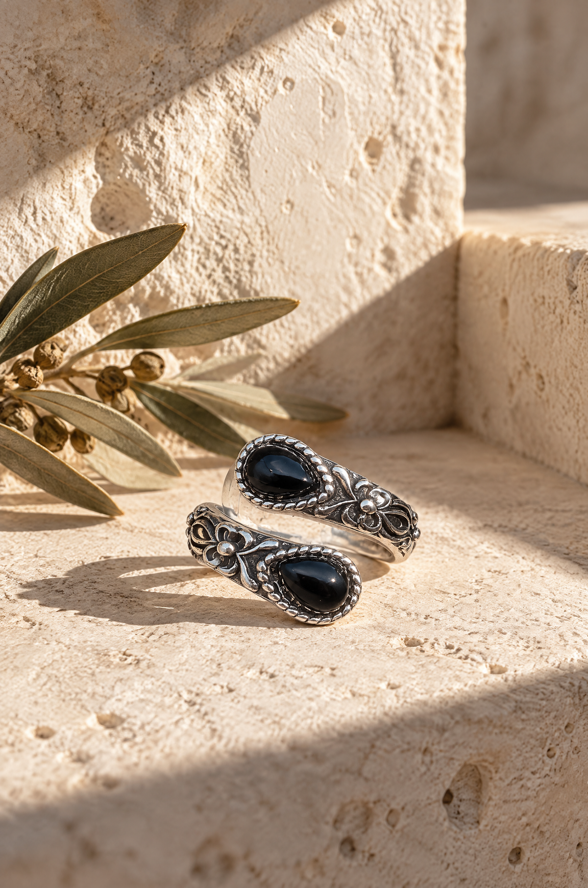 Ponza wrap ring, obsidian, in a travertine niche