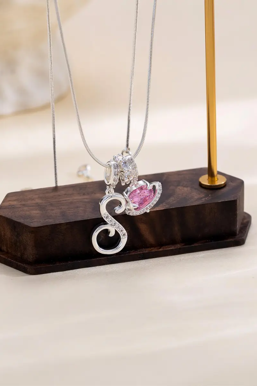 Cifra initial necklace displayed on a walnut block