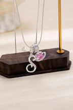 Cifra initial necklace displayed on a walnut block