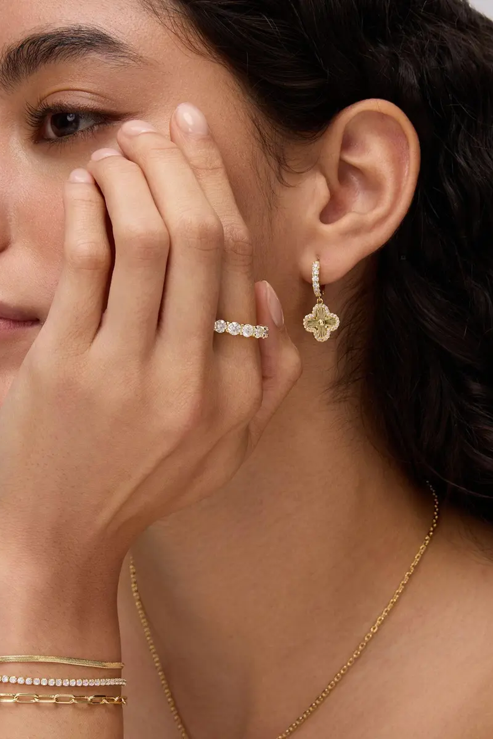 Fortuna clover earring worn with a hand resting against the face