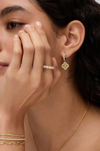 Fortuna clover earring worn with a hand resting against the face