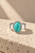 Giglio ring cover with a turquoise stone on travertine