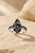 Ombra obsidian flower ring on warm travertine stone
